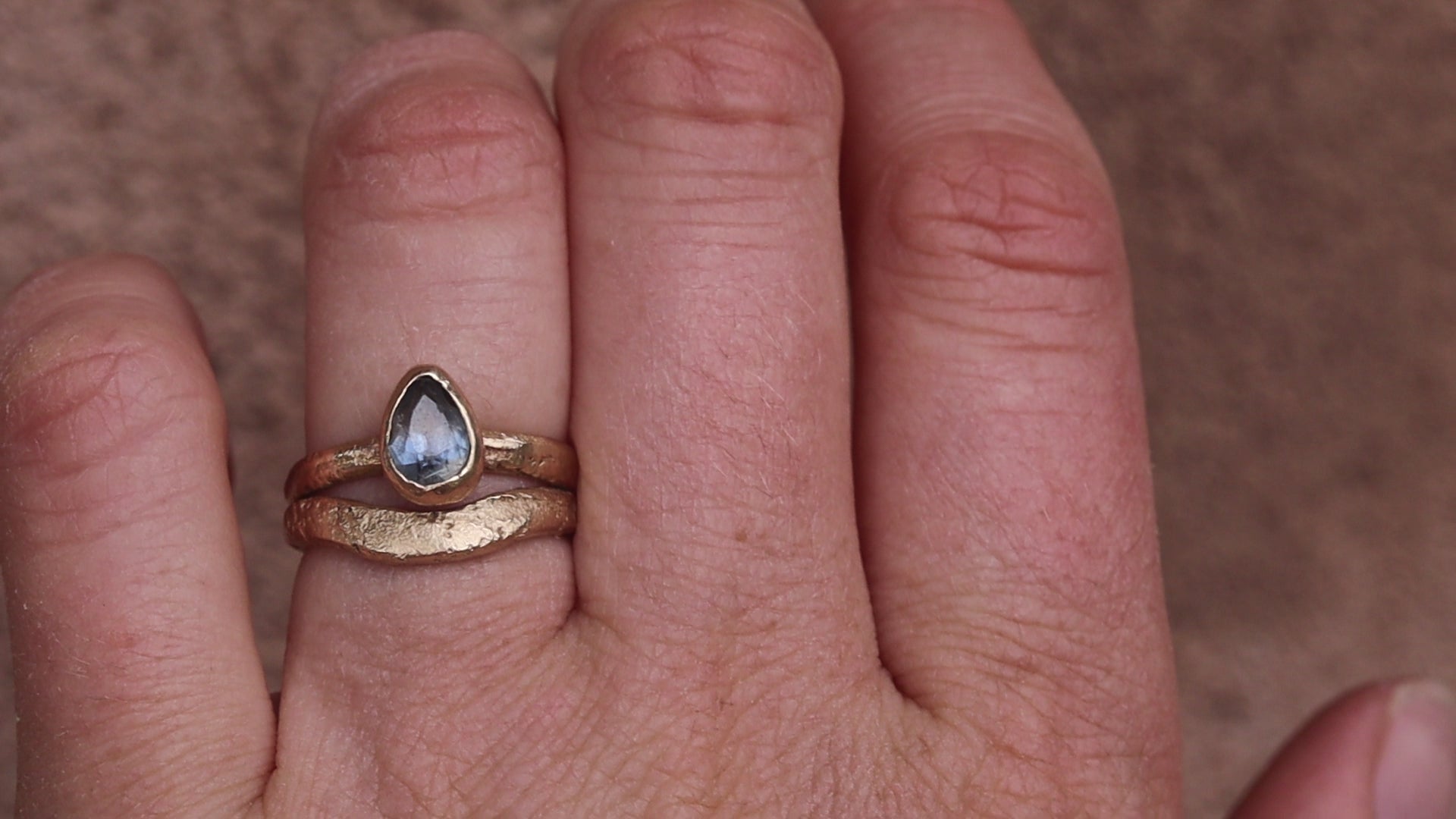 organic texture sandcast paige devlin jewelry 14kt gold handcrafted engagement ring arc curve band pear blue montana sapphire